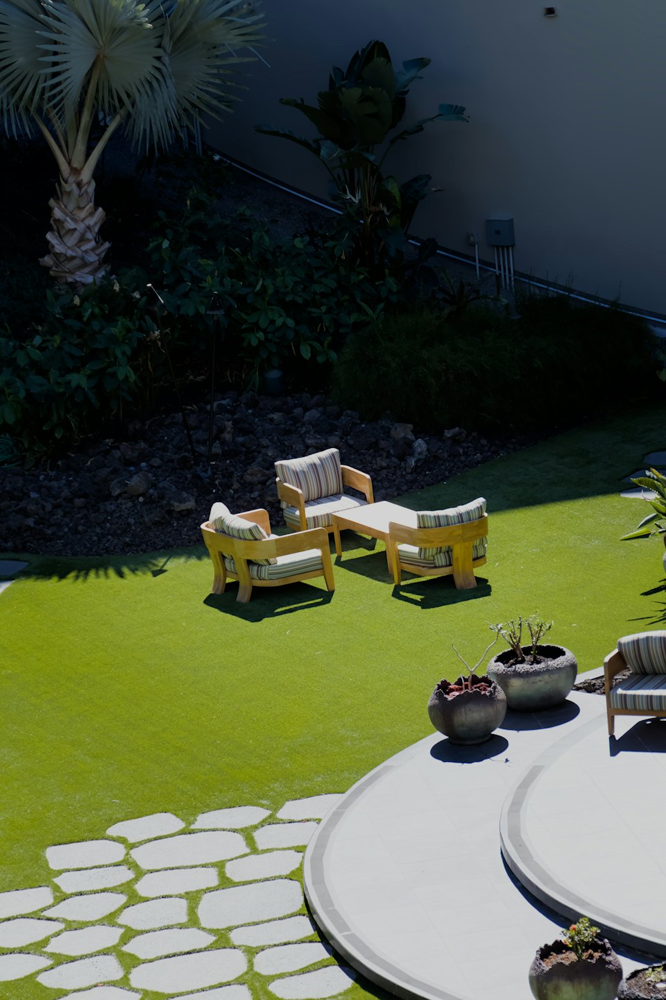 Wooden patio furniture set arranged on a green lawn.